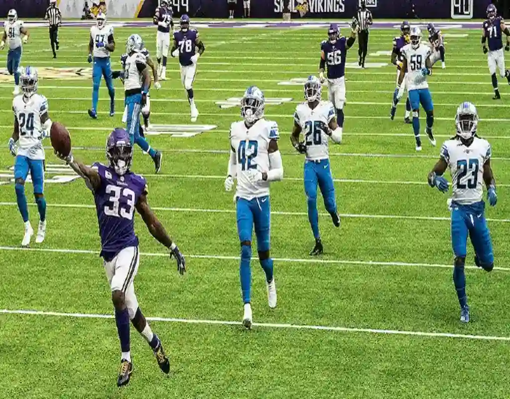 Minnesota Vikings player sprints past Detroit Lions defenders during NFL game touchdown run
