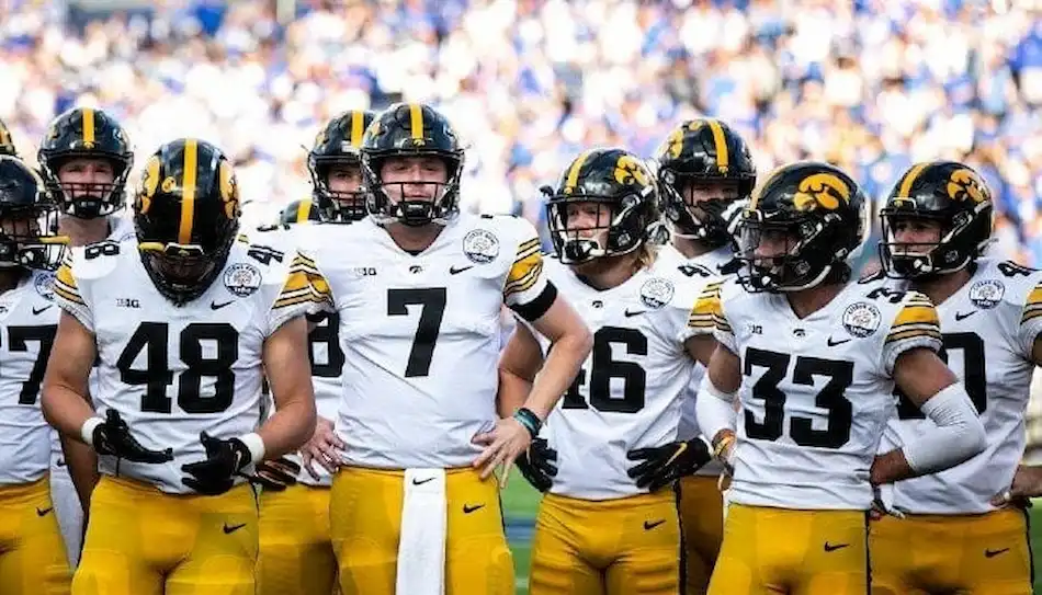 Iowa Hawkeyes football team huddles together on the field.