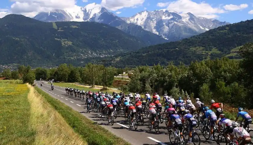 Gambling News 7 A large group of cyclists races down a scenic road.