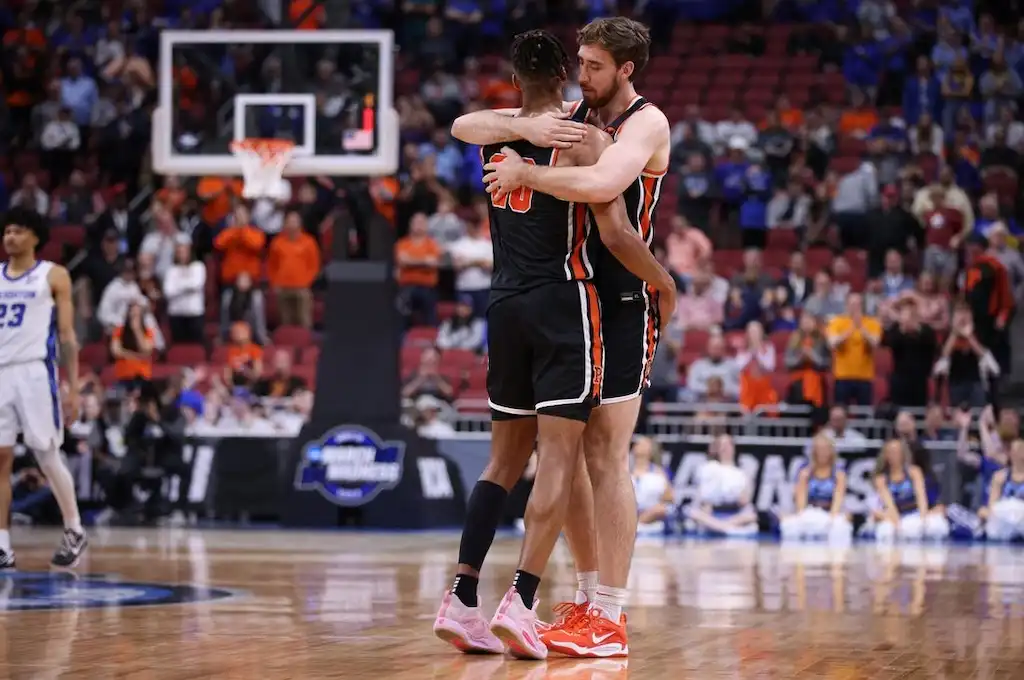 NCAAB 4 Two Princeton basketball players in black uniforms embrace on the court.
