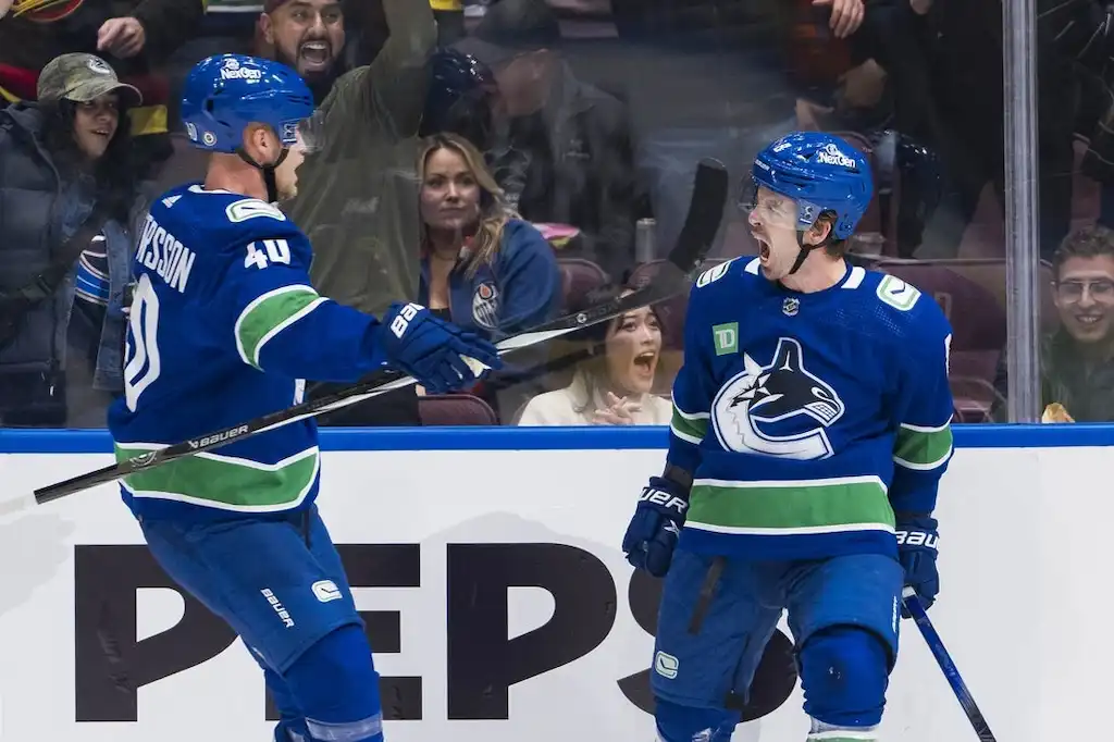 Previews 6 Two Vancouver Canucks players celebrate on the ice in front of excited fans during a game.