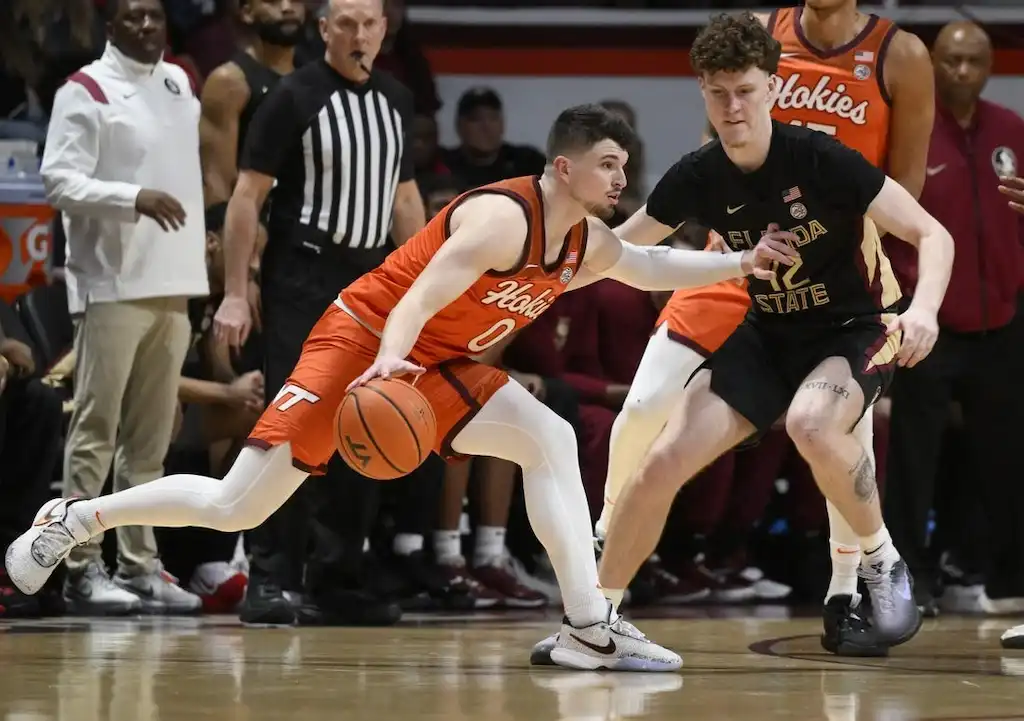NCAAB 2 A Virginia Tech player dribbles the ball while closely guarded by a Florida State.