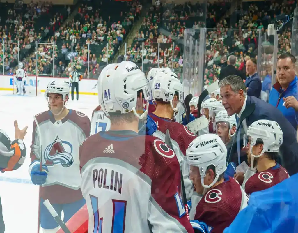 Colorado Avalanche players gather around the coach during a timeout in an NHL game