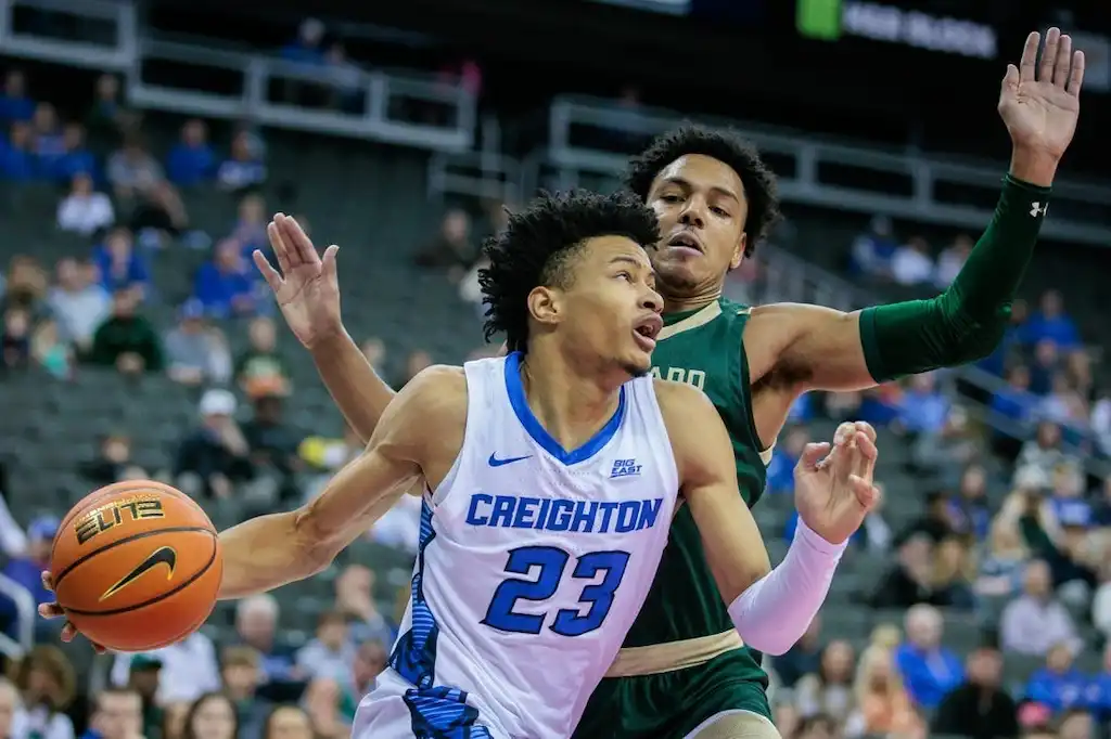 NCAAB 2 A Creighton basketball player drives to the basket while being closely guarded by a defender.