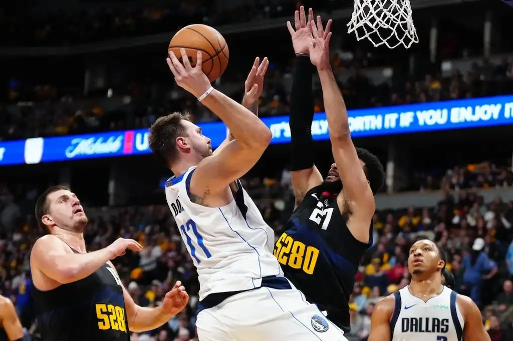 A Dallas Mavericks player goes up for a contested shot near the basket.