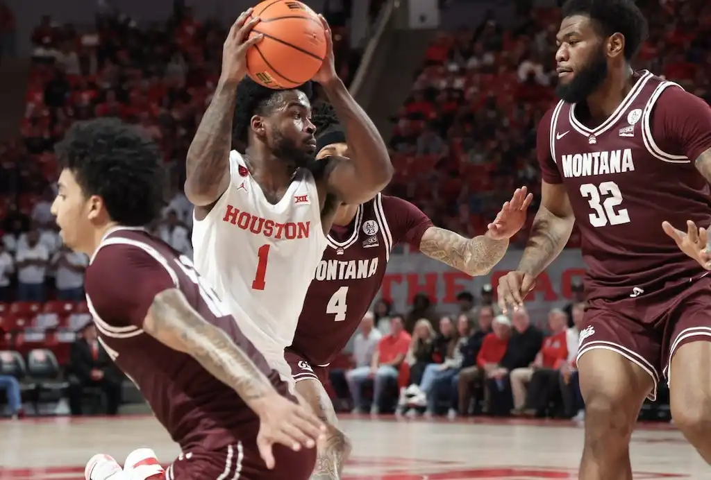 A Houston basketball player holds the ball above his head.