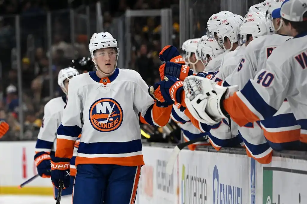 NHL 10 New York Islanders player skates past the bench and fist bumps teammates after a play.