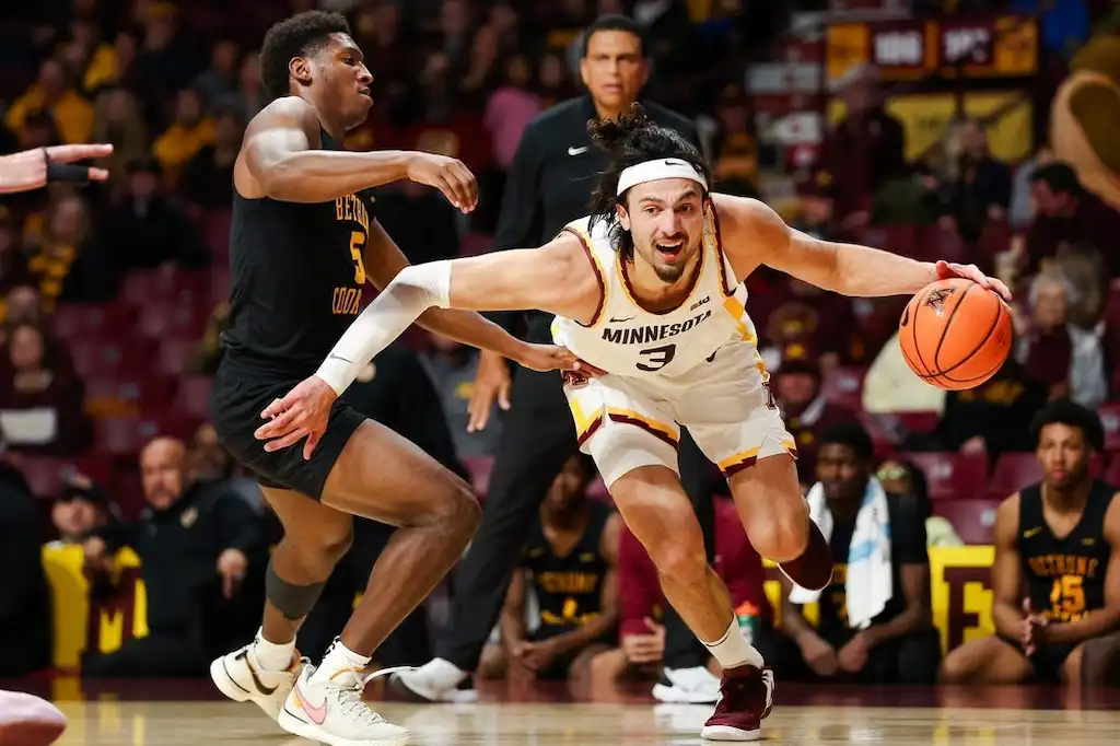 Minnesota player drives past a defender while holding the ball.