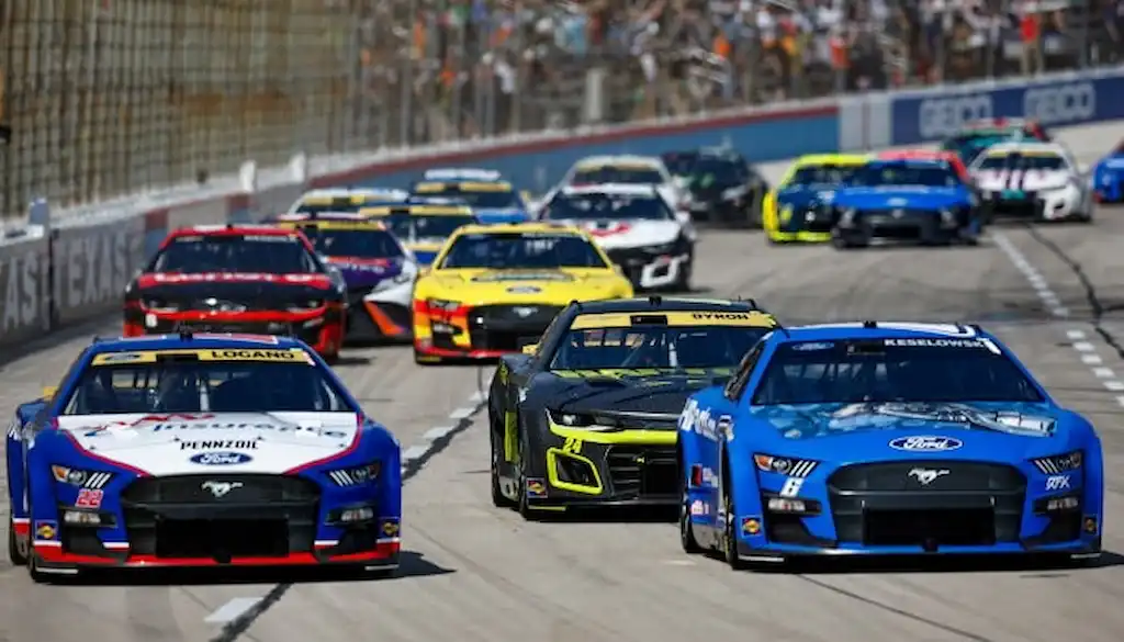 Gambling News 7 A pack of NASCAR race cars speeds down the track at Texas Motor Speedway.