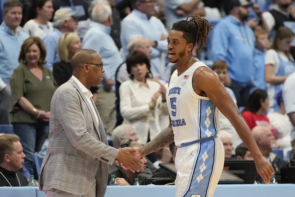 A North Carolina basketball player shakes hands with a coach.