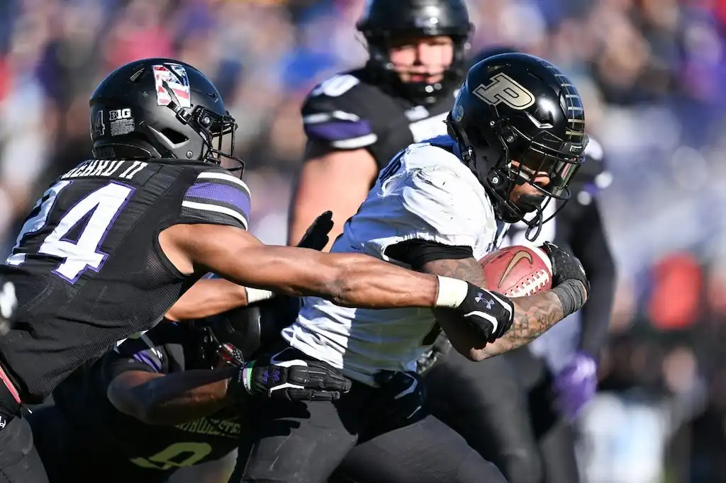A Purdue football player while being tackled by a Northwestern defender.