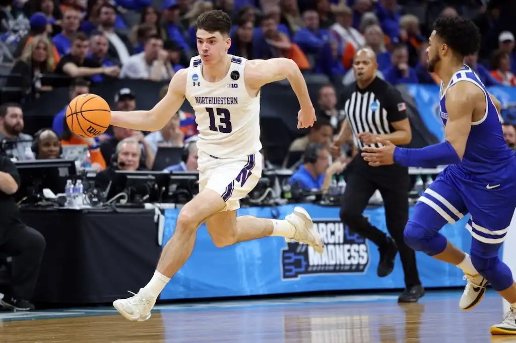 Northwestern basketball player dribbles the ball down the court during an NCAA March Madness game.
