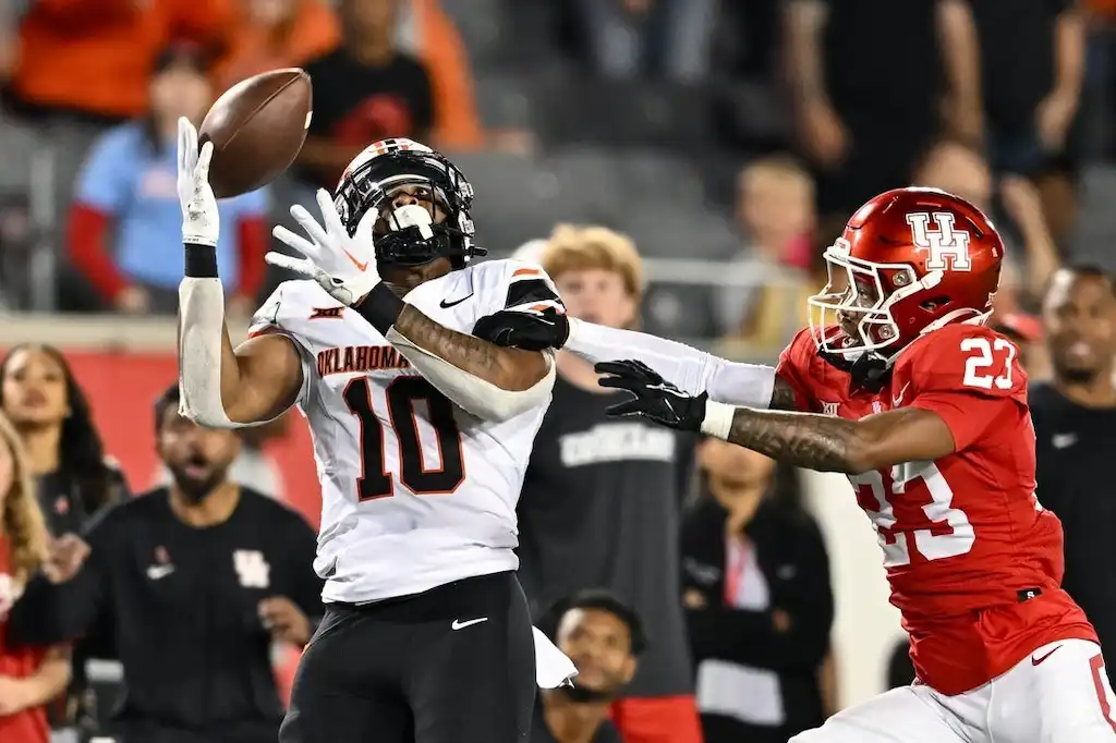 An Oklahoma State football player reaches up to catch a pass.