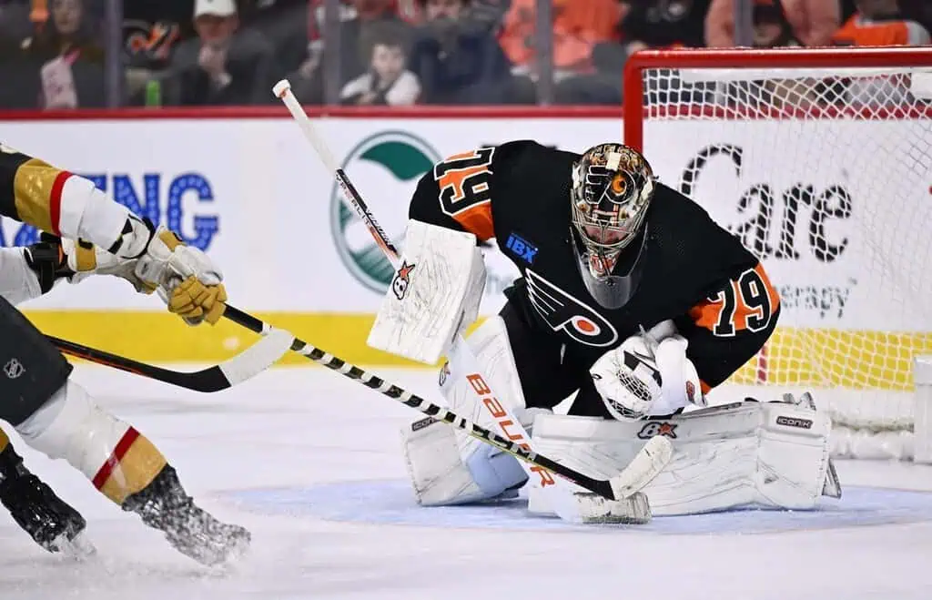 Philadelphia Flyers goalie making a save against a Vegas Golden Knights player.