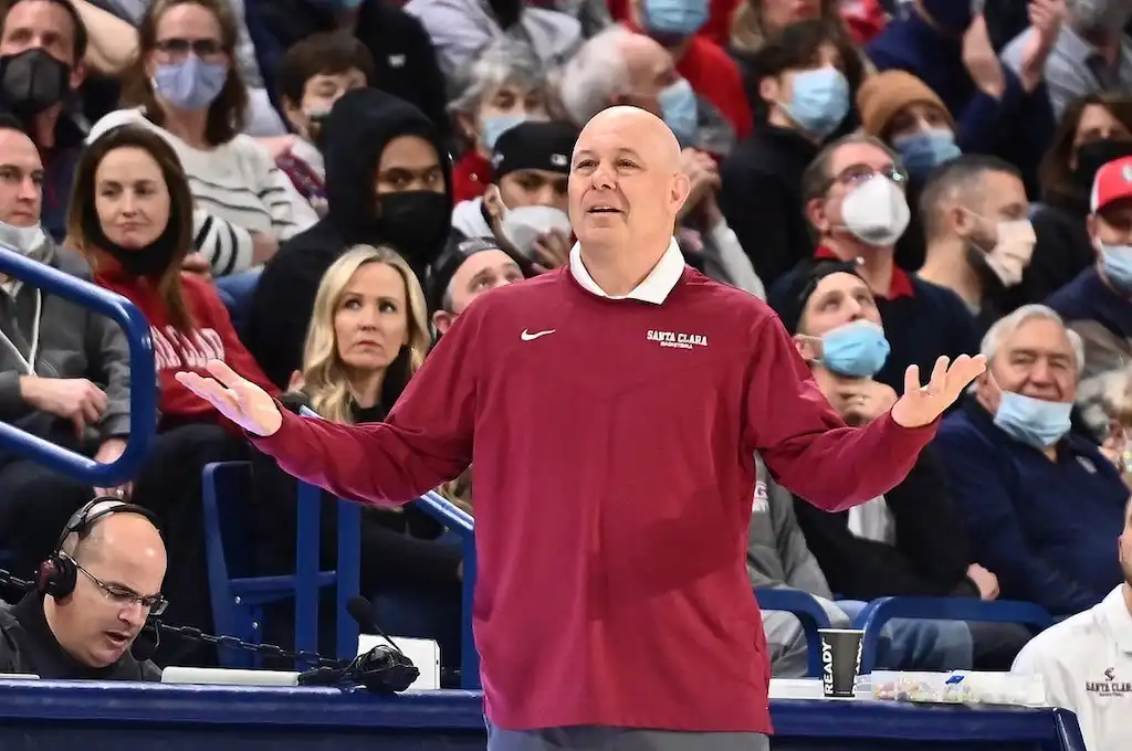 Santa Clara basketball coach gestures in disbelief or confusion on the sideline.