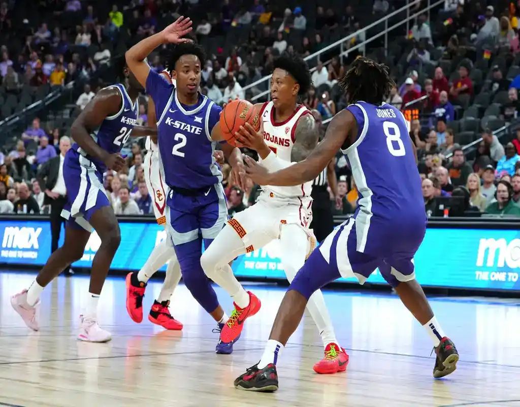 USC Trojans player drives through Kansas State defenders during a college basketball game