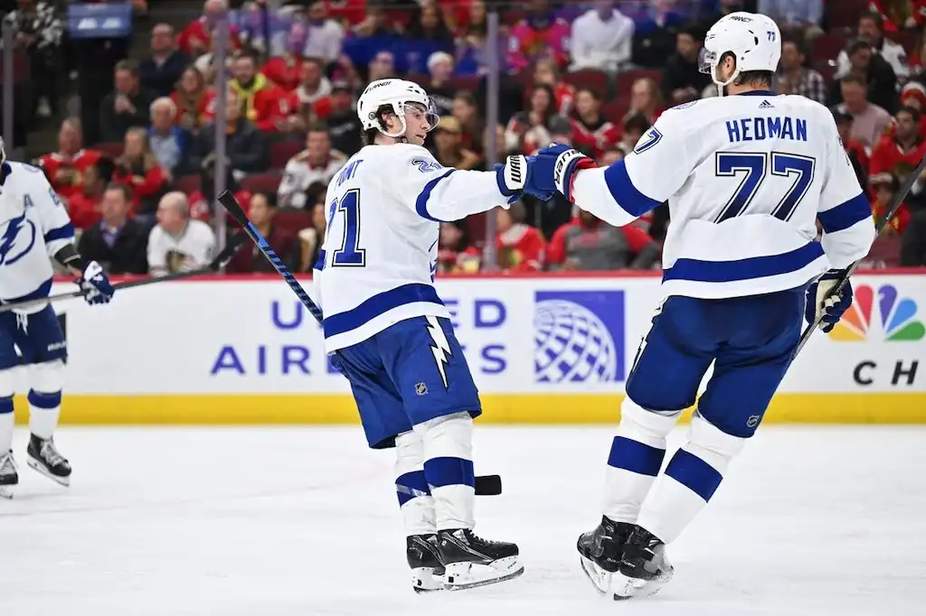 Two Tampa Bay Lightning players celebrate on the ice with a fist bump during a game.