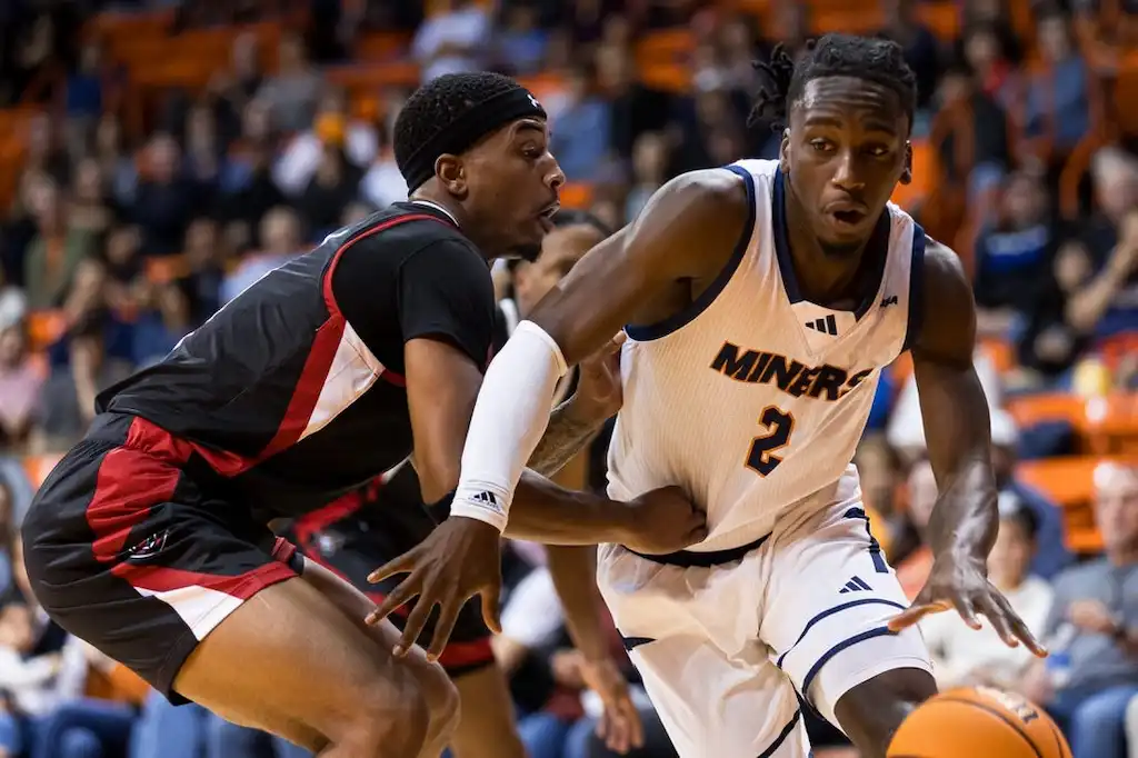 NCAAB 6 A UTEP Miners basketball player drives past a defender in black and red.