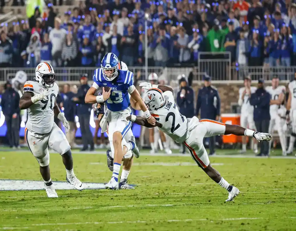 Duke Blue Devils quarterback breaks a tackle from a Virginia Cavaliers defender during a game on November 18, 2023.