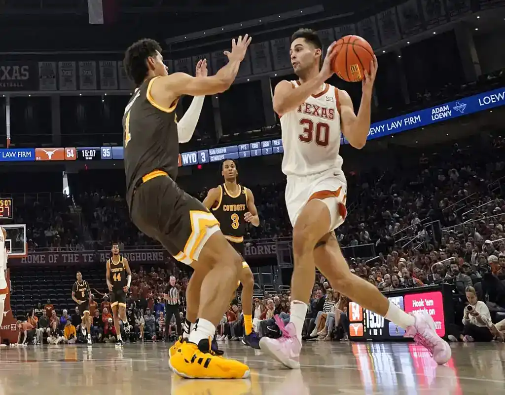 NCAAB 1 Texas Longhorns player drives toward the basket while defended by a Texas State Bobcats player during their game on November 30, 2023.