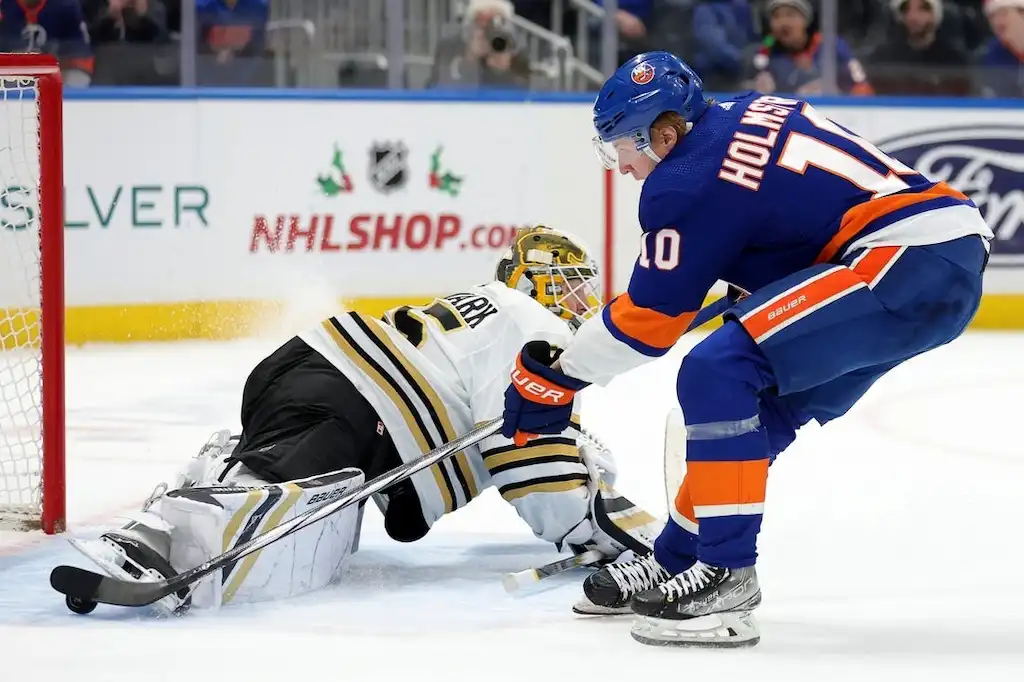 A New York Islanders player attempts to score against the Boston Bruins goalie.