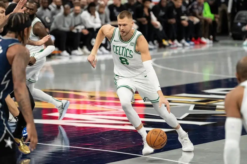 A Boston Celtics player dribbles the basketball aggressively toward the paint.