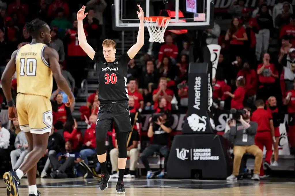 NCAAB 7 A Cincinnati basketball player raises both arms in celebration after a play.