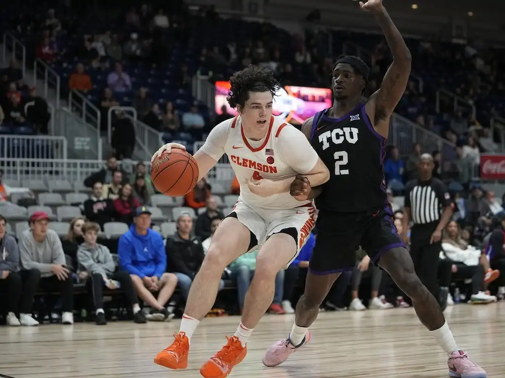 NCAAB 8 A Clemson basketball player drives toward the basket while being closely guarded by a TCU defender.