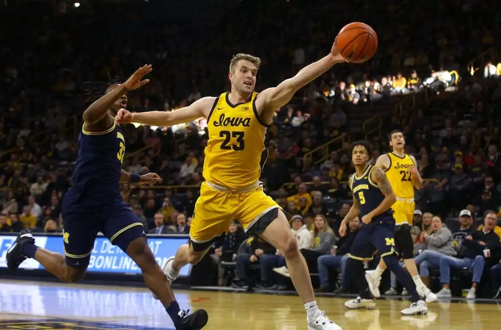An Iowa basketball player stretches out to save the ball from going out of bounds.