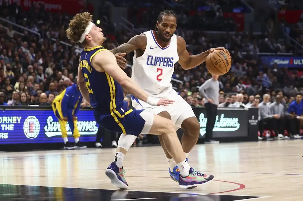 5 LA Clippers player drives to the basket with the ball as a Golden State Warriors defender falls.