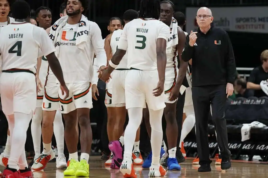 Miami Hurricanes men's basketball team huddles near the bench.