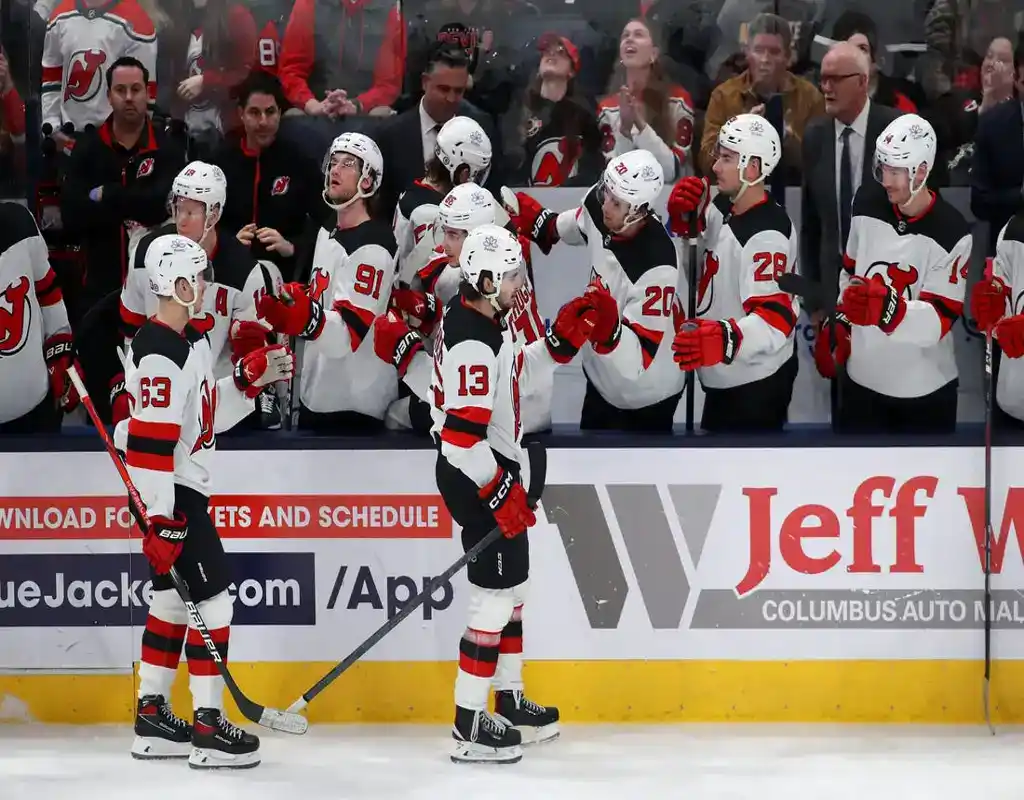New Jersey Devils players congratulate a teammate at the bench during NHL game against Anaheim Ducks
