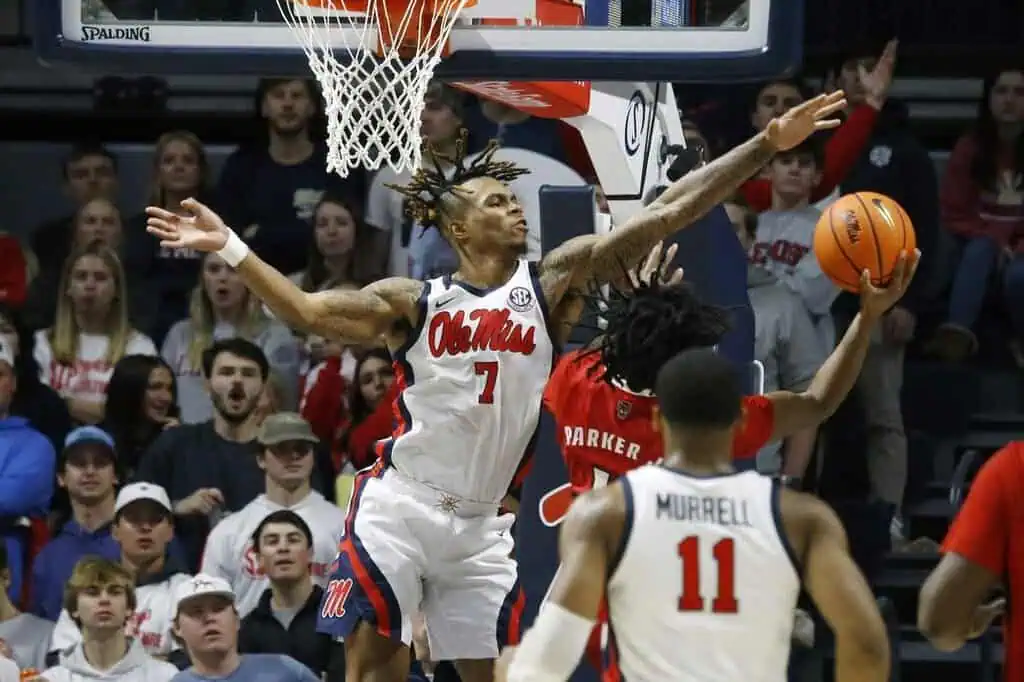 NCAAB 9 This is an action-packed basketball image showing Ole Miss player attempting to block a shot from an opposing player in red.