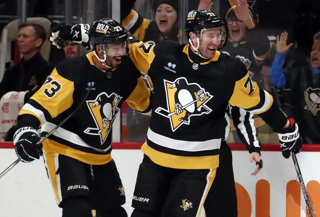 Pittsburgh Penguins players celebrate on the ice after a goal during an NHL game.