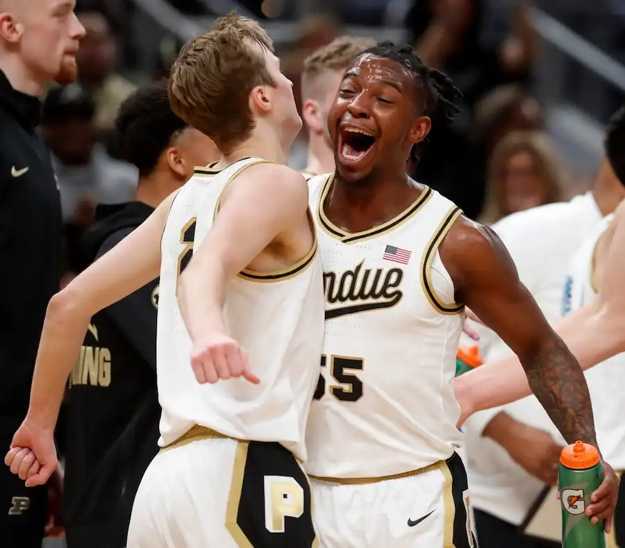 NCAAB 6 Two Purdue basketball players celebrate on the sideline with excitement during a game.