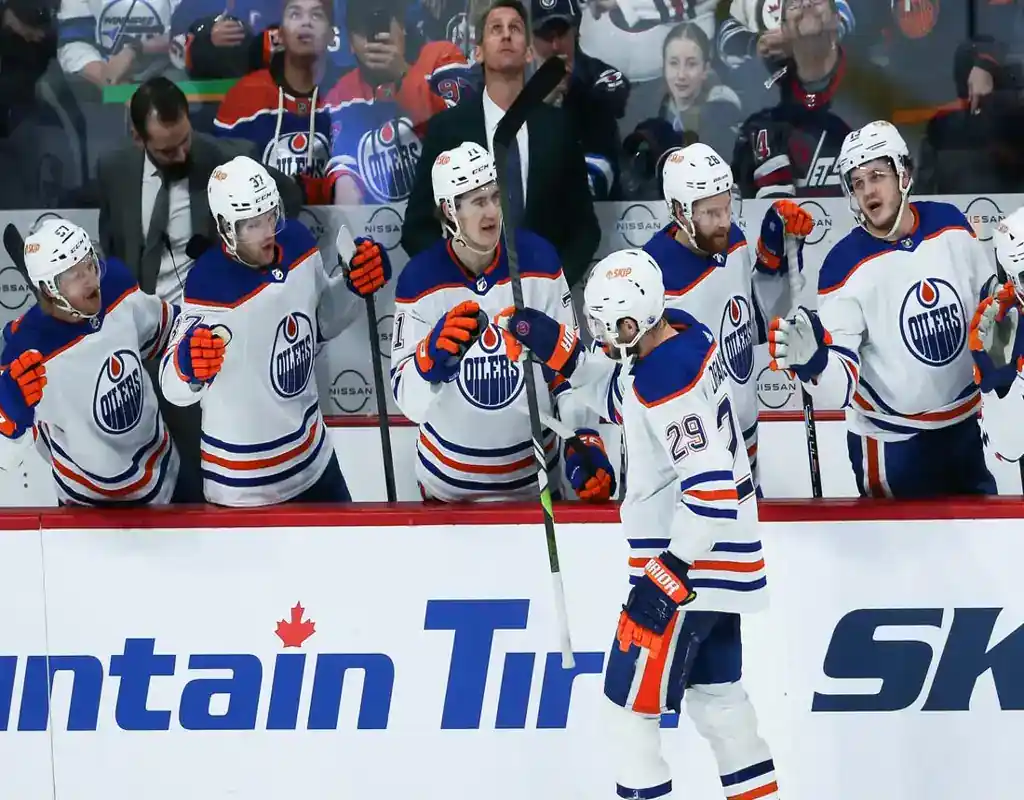 NHL 9 Edmonton Oilers players celebrating near the bench during a hockey game against the Carolina Hurricanes