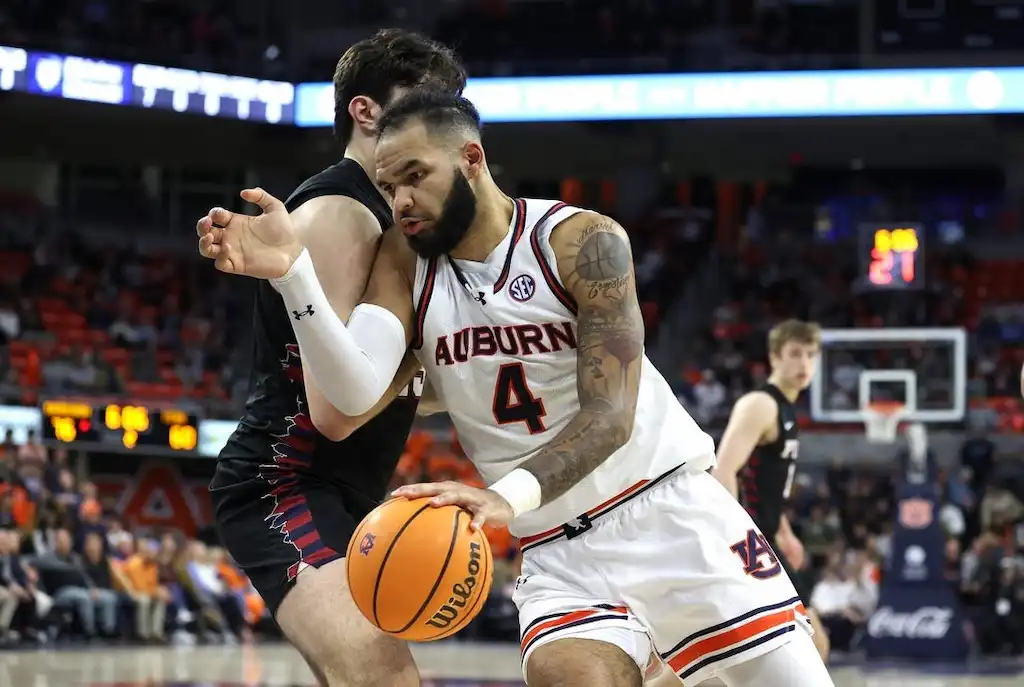NCAAB 7 An Auburn player drives aggressively toward the basket while being closely guarded by a defender