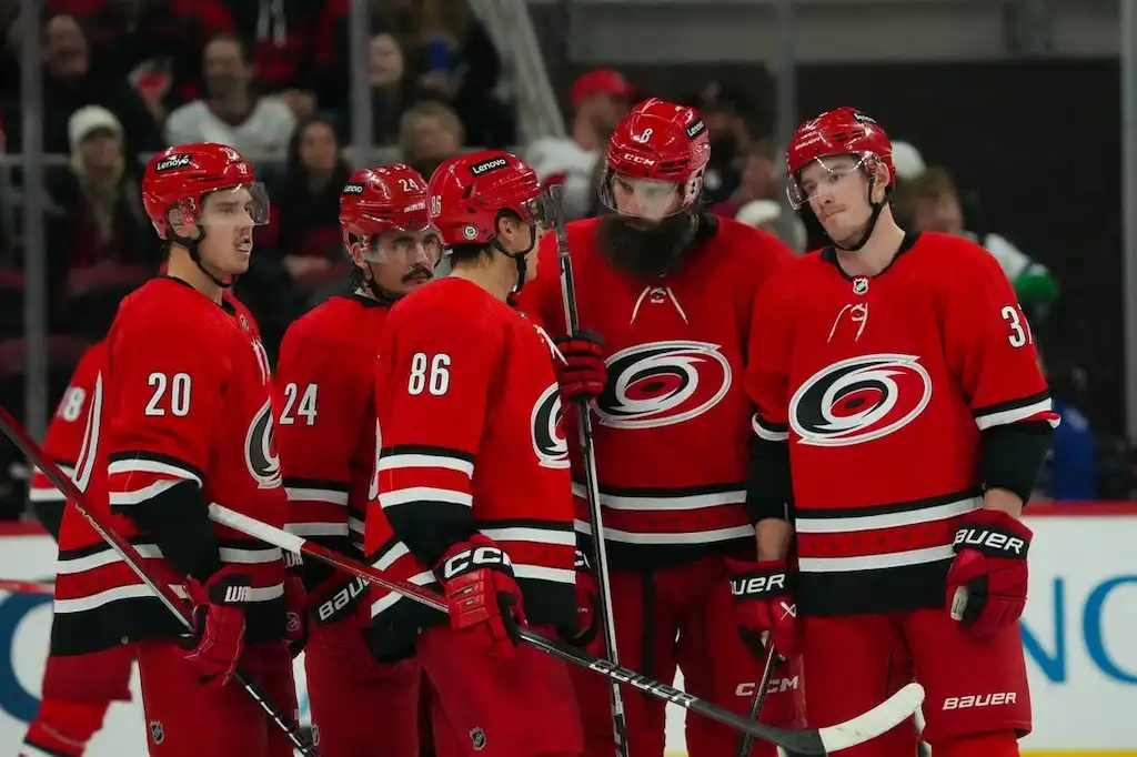 Carolina Hurricanes players huddle together on the ice during a break in play.