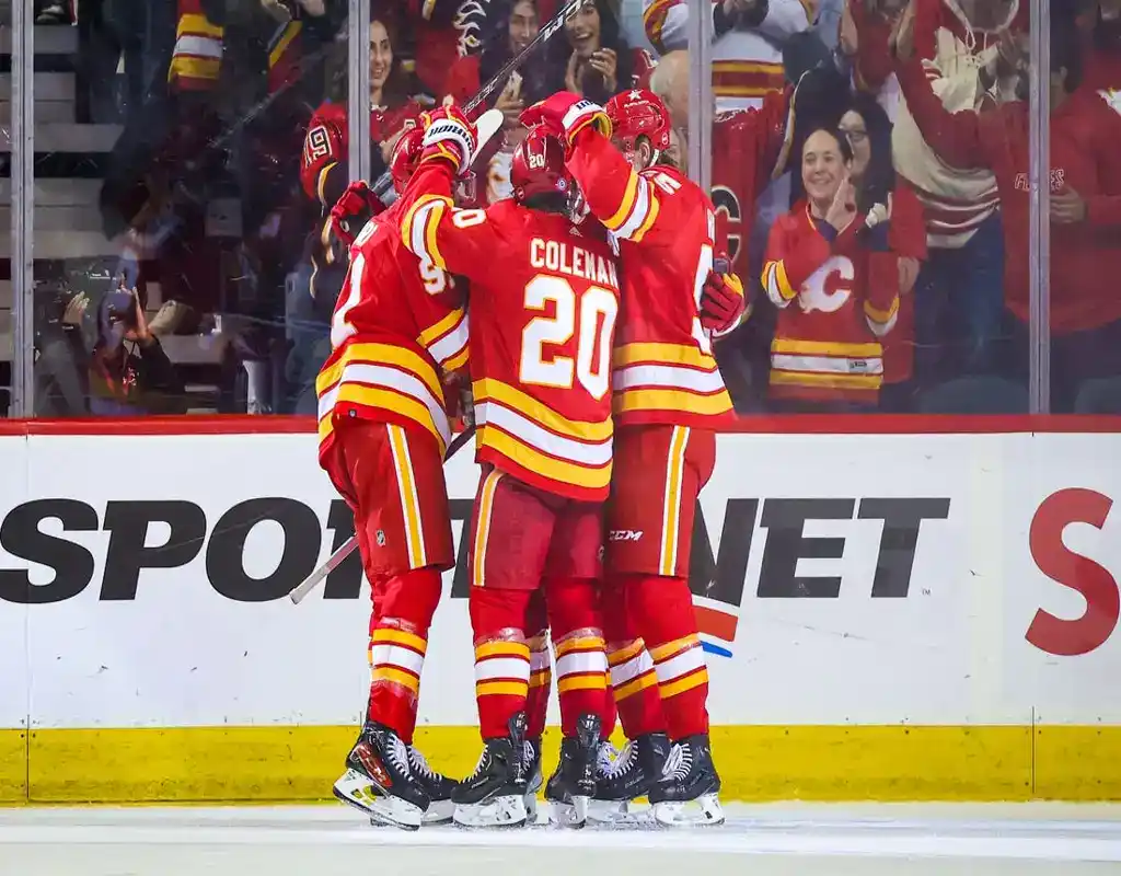 Calgary Flames players celebrate together on the ice after scoring a goal against the Arizona Coyotes