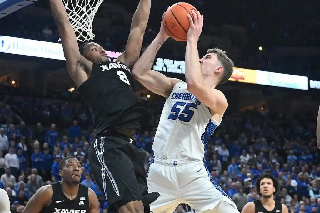 Creighton player goes up for a shot while a defender jumps to block near the rim.