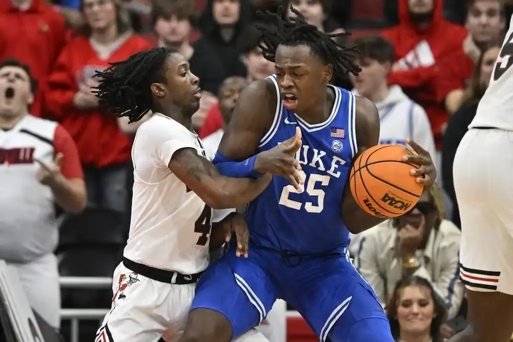 NCAAB 2 A Duke basketball player battles for position while holding the ball tightly against a Louisville defender.