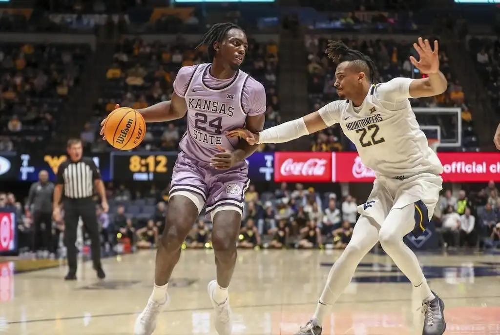 Kansas State player looks to make a move while being closely guarded by a defender.