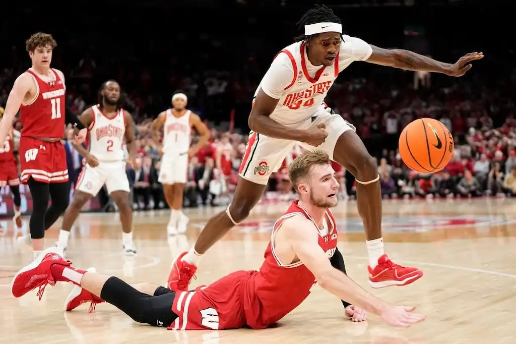 An Ohio State player leaps over a Wisconsin player diving for a loose ball.