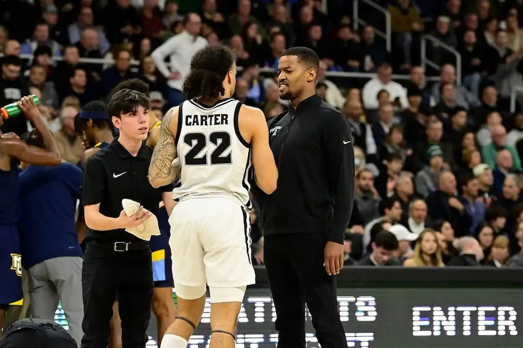 A providence basketball player has an intense conversation with a coach on the sideline.