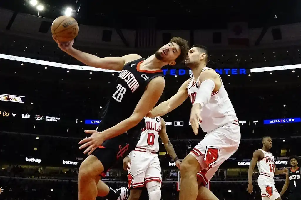 Houston Rockets player drives to the basket while being closely defended by a Chicago Bulls player.