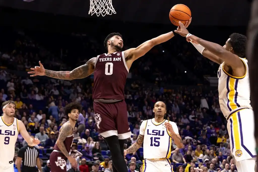 A Texas A&M player leaps with his arm fully extended to contest a shot.
