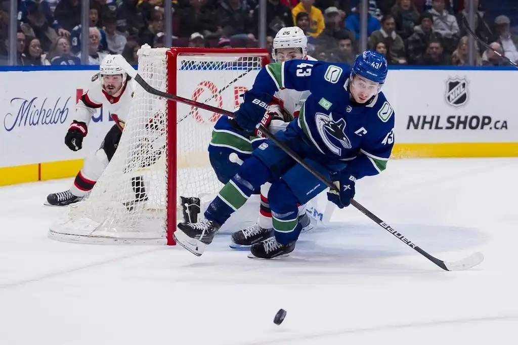 NHL 7 A Vancouver Canucks player maneuvers the puck behind the net.