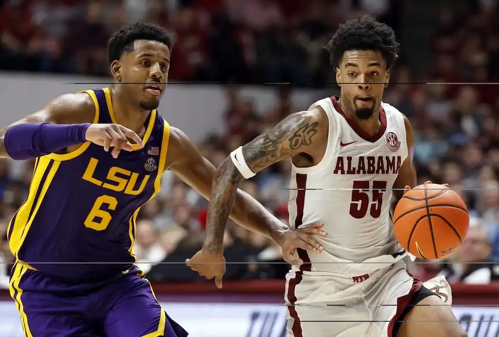 NCAAB 1 An Alabama basketball player dribbles the ball upcourt while being closely defended by an LSU player.