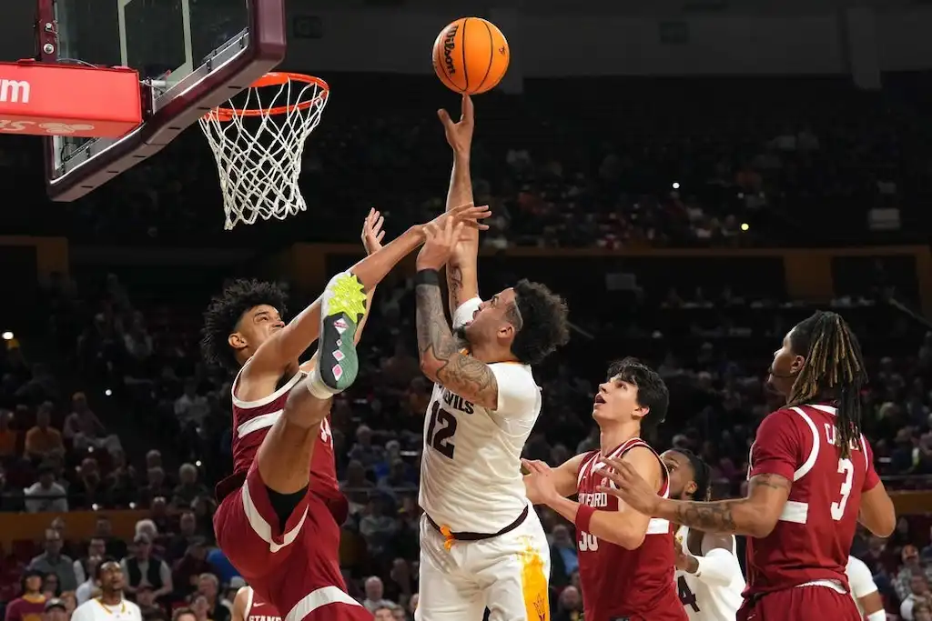 An Arizona State basketball player attempts a contested layup against multiple defenders.