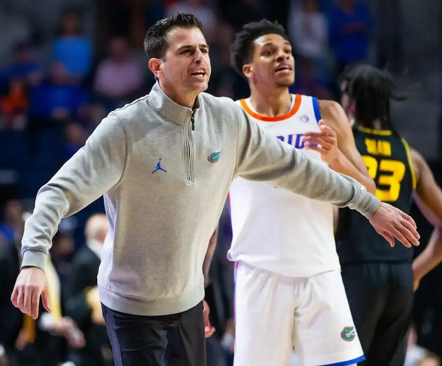 A Florida Gators basketball coach gestures passionately on the sideline during a game.